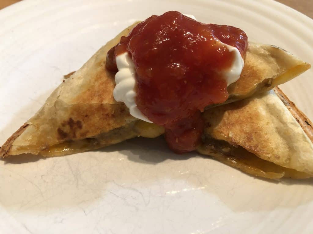 pie iron tasty taco with sour cream and salsa on a white plate
