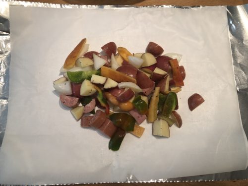 sausage peppers onions potatoes on parchment and foil