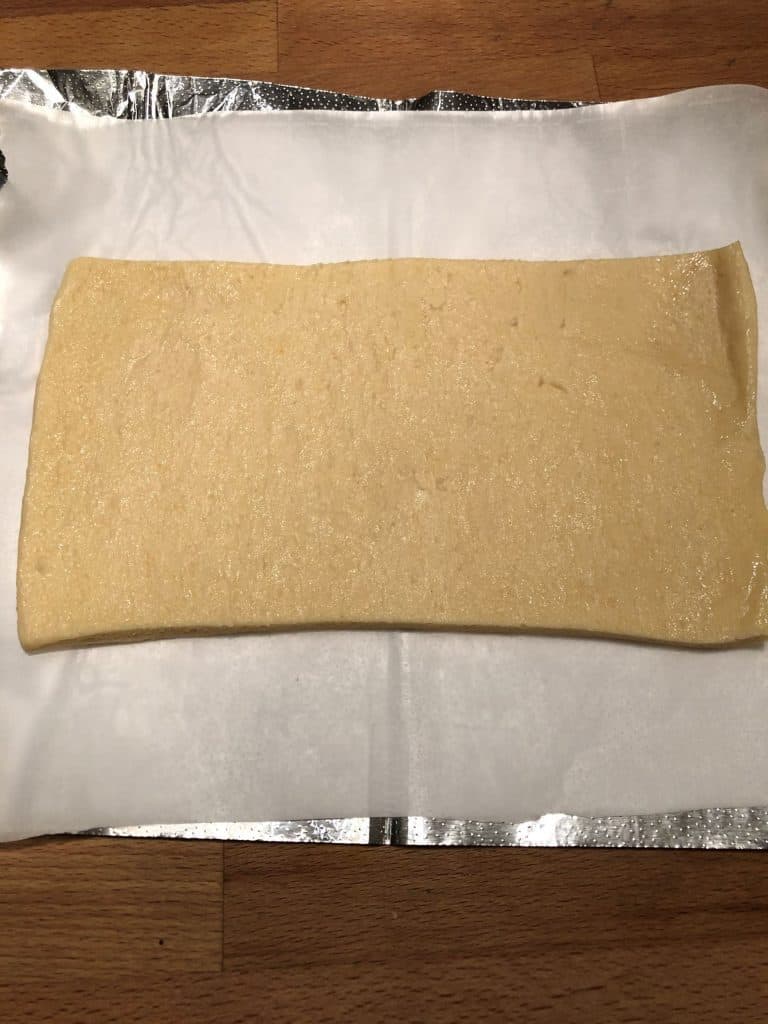 pizza dough on parchment paper and heavy duty foil