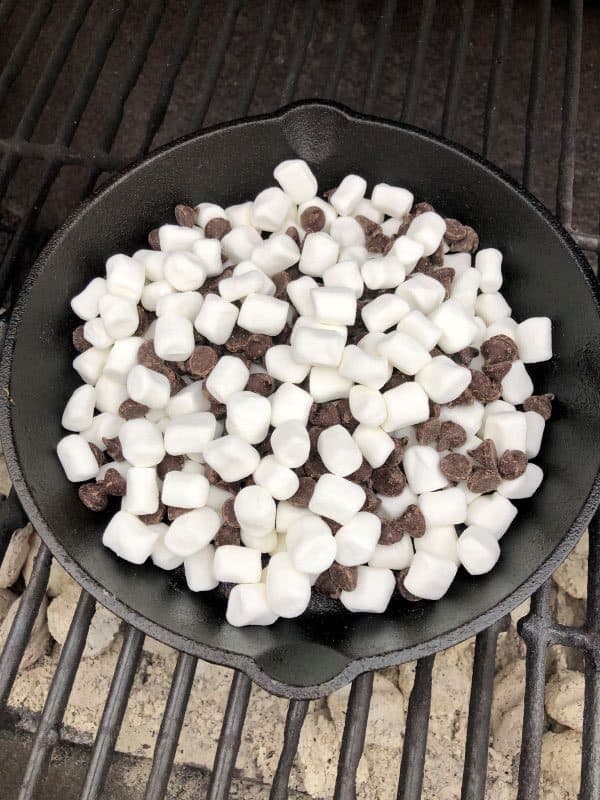 marshmallows and chocolate in cast iron skillet on grill