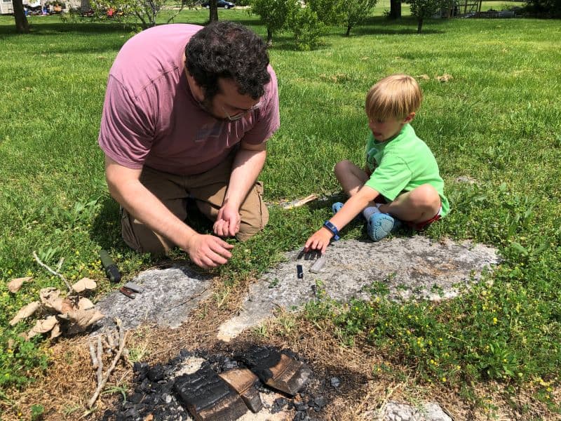 adult and child using rod to make sparks for fire