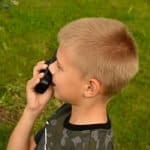 blond boy on walkie talkie while camping in green field