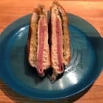 Ham and Swiss sandwiches with poppyseed sauce melted on a blue plate