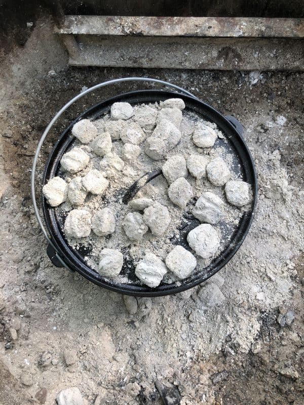 Dutch oven covered in gray coals