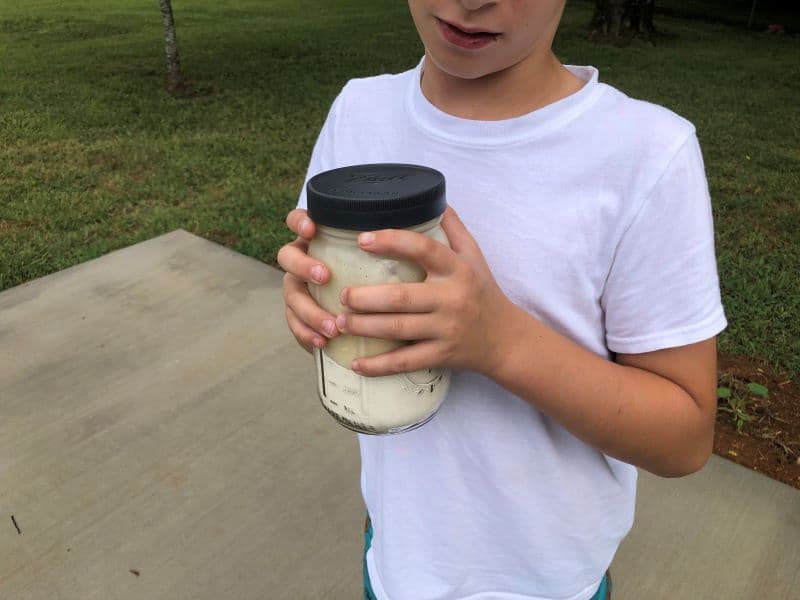 kid holding mason jar mixing ingredients for pie iron breakfast puffs