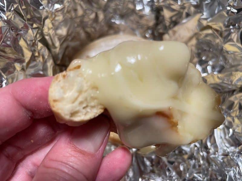 hand holding melted brie on piece of bread