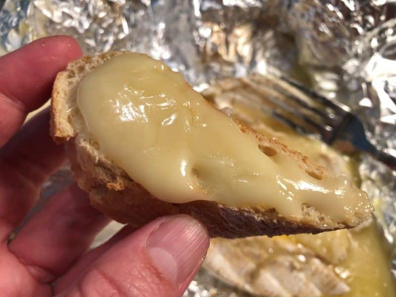 hand holding slice of bread with melted brie