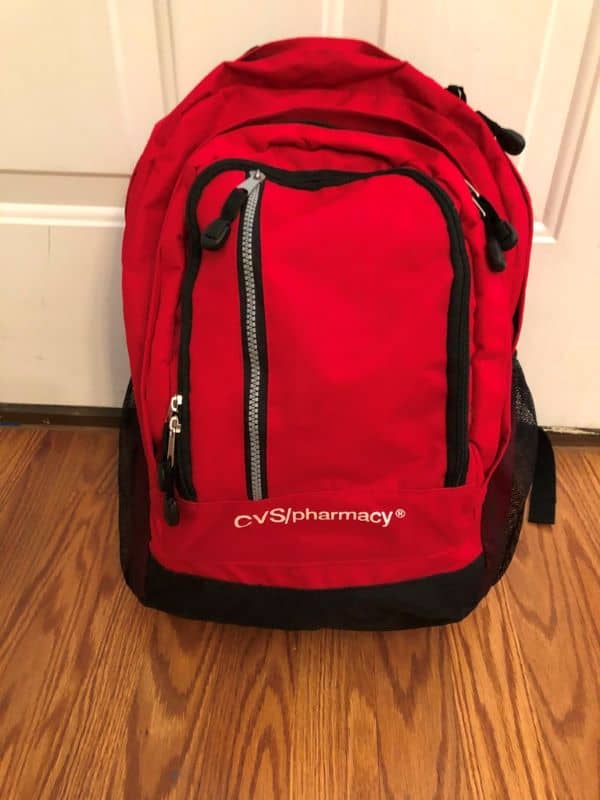 red backpack sitting on floor in front of white door