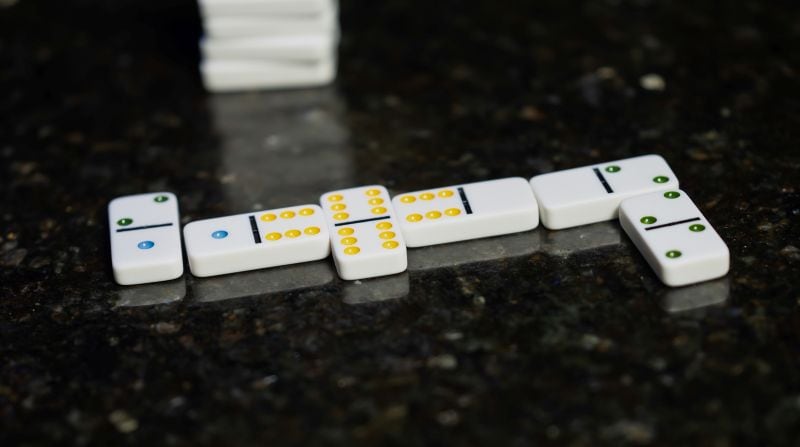 white dominoes with colored pips laid out on black marble surface